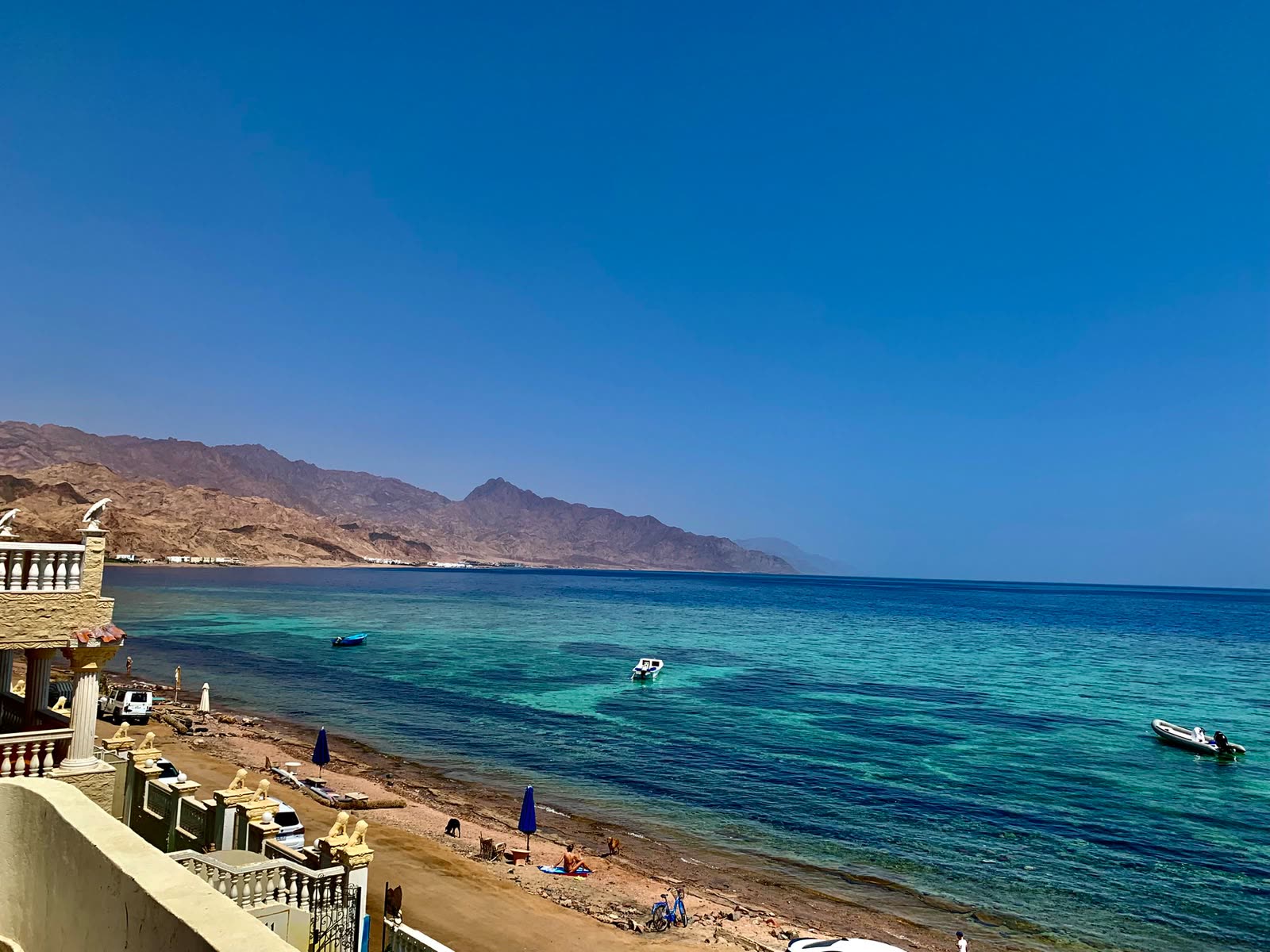 The bay at Dahab from above, turquoise water along the beach and mountains behind.