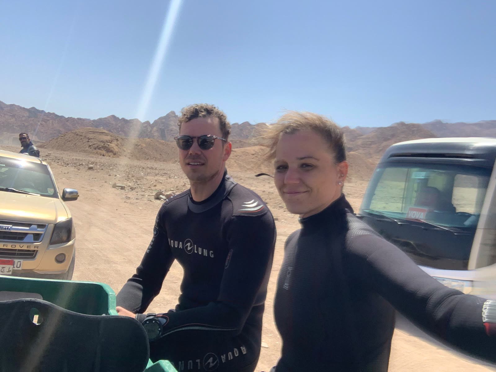 Two divers in wetsuits standing beside a four-by-four in the desert near Dahab.