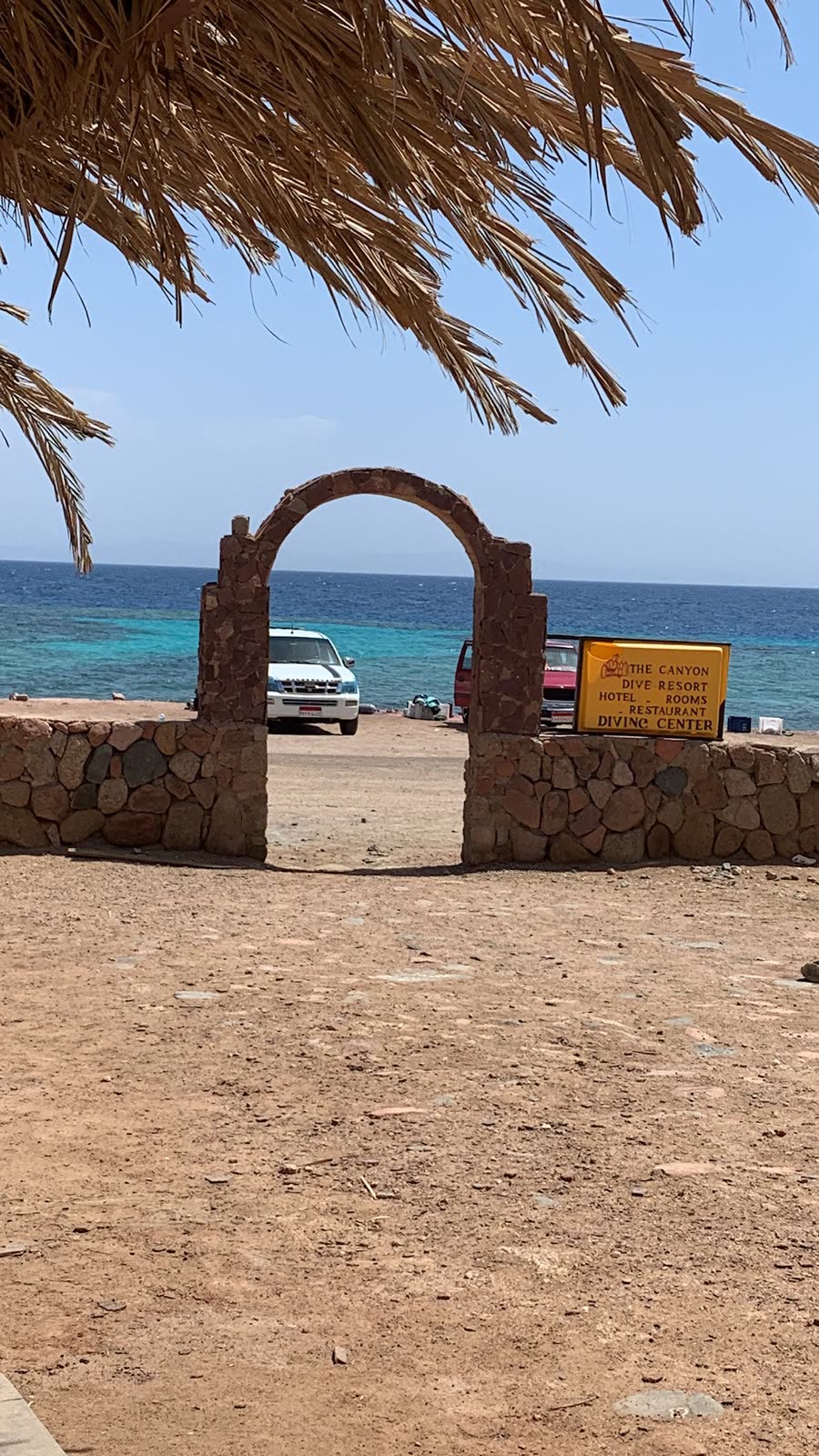 A stone archway on the shore, the sea visible through it.