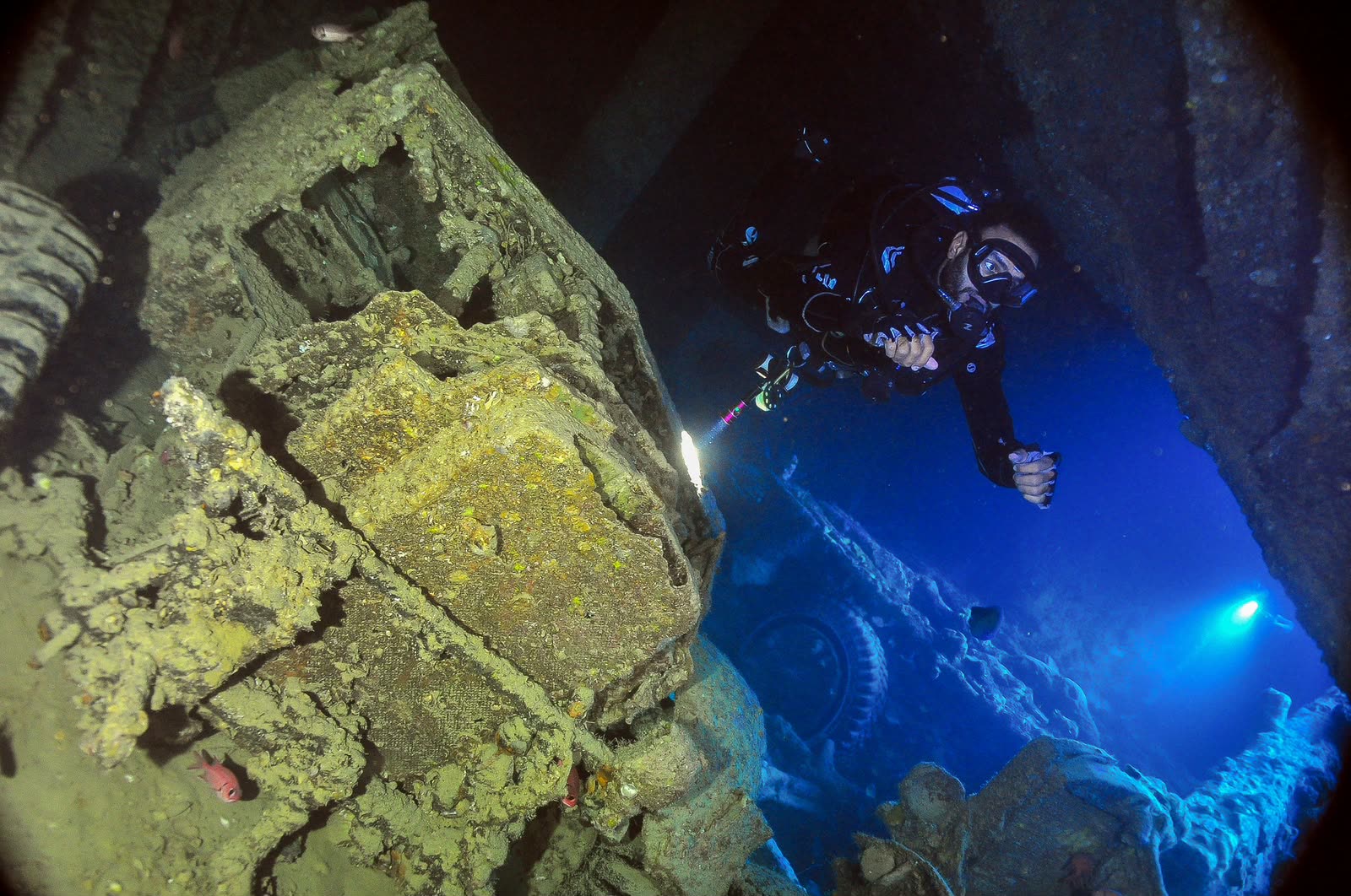 Cargo in the hold of the wreck, a diver with a torch beyond.